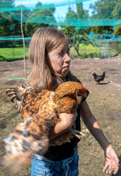 Chica rural con gallina marrón. - Foto, imagen