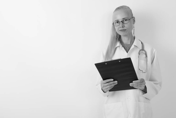 Beautiful blond woman doctor wearing eyeglasses against white background - Fotó, kép