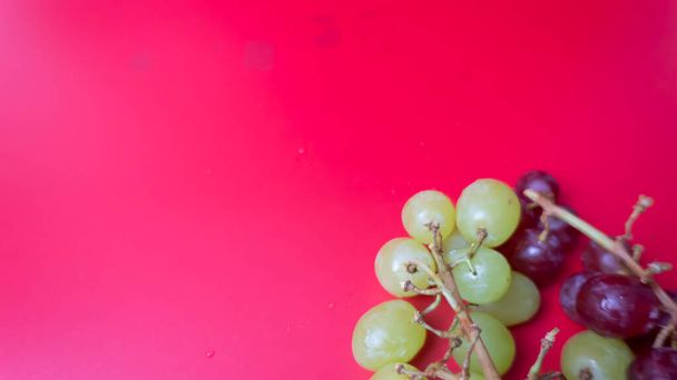 Uvas frescas vermelhas e verdes isoladas sobre fundo rosa. Foco seletivo nas uvas frescas vermelhas e verdes. - Foto, Imagem