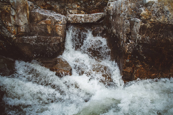 Река между камнями и камнями. Река в каменном слое, быстрая горная река среди скал, вода кипит в вихрях течения. - Фото, изображение
