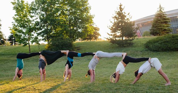 Un grupo de personas hace yoga en el Parque al atardecer. Vida sana, meditación y bienestar - Foto, imagen