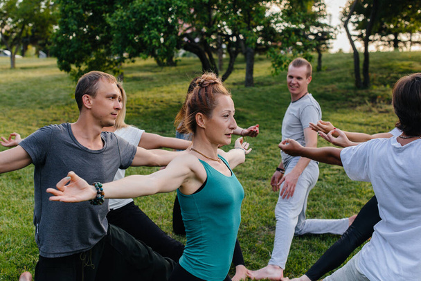 A group of people do yoga in a circle in the open air during sunset. Healthy lifestyle, meditation and Wellness - Valokuva, kuva