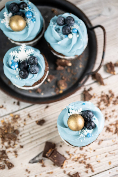 Several muffins or cupcakes with blue shaped cream and blueberrieson at white table. Rustic style copyspace. - Φωτογραφία, εικόνα