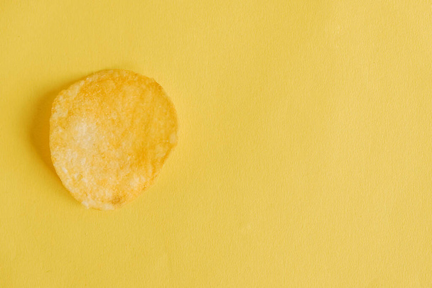 Potato chip on a yellow background. Top view. Copy, empty space for text. - Valokuva, kuva