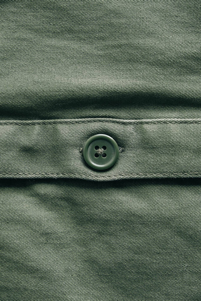 Groene knop op groene jas. Kleding detail. Bovenaanzicht. Kopieer, lege ruimte voor tekst. - Foto, afbeelding