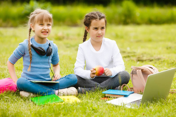Lapset piknikillä koulun pihalla tulevat syömään lounasta laatikossa. vanhempi hoitaa lastenhoitoa. - Valokuva, kuva