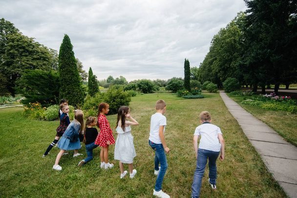 A group of school children runs in the Park in the summer. Happiness, lifestyle. Happy childhood - Foto, immagini