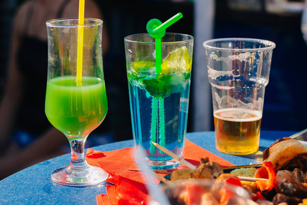 Очки с алкогольными коктейлями и стакан с пивом на открытом воздухе. Вечеринки. - Фото, изображение