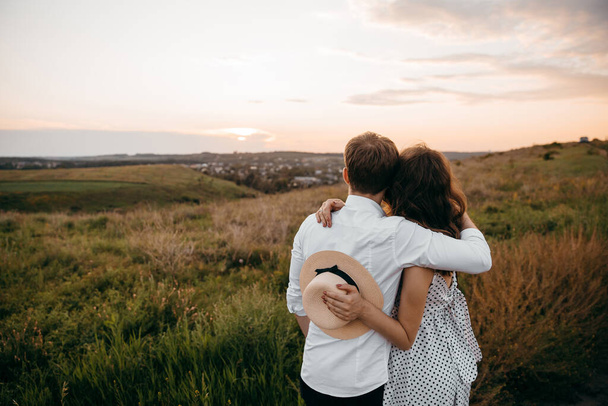 Una giovane coppia amorevole che si abbraccia sullo sfondo del tramonto della natura - Foto, immagini