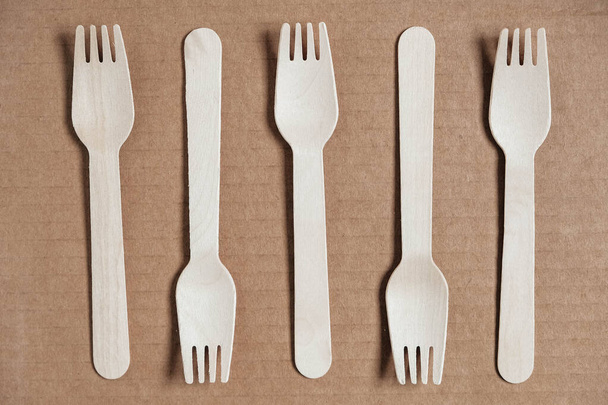 Wooden forks on a cardboard background. Eco friendly disposable tableware. Top view. Copy, empty space for text. - Photo, Image
