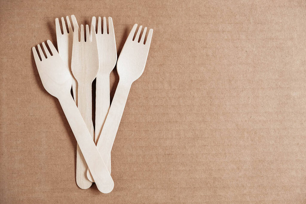 Wooden forks on a cardboard background. Eco friendly disposable tableware. Top view. Copy, empty space for text. - Photo, Image