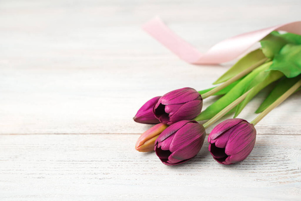 Un ramo de flores de tulipanes púrpura sobre un fondo claro de madera. - Foto, Imagen