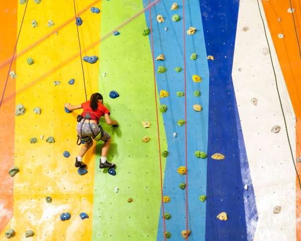 Pequeña niña escalada pared de roca pared práctica en el gimnasio - Foto, Imagen