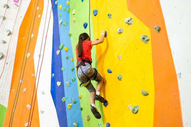 Pieni tyttö kiipeily Rock Wall käytännön seinä kuntosalilla - Valokuva, kuva