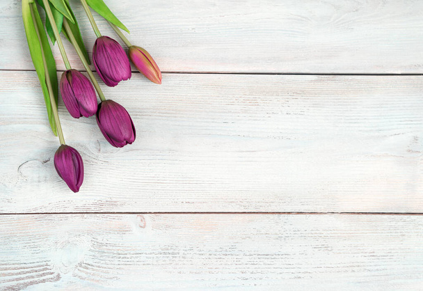 Fond fleuri, Bouquet avec tulipes sur fond bois blanc. Vue de dessus, avec espace pour copier. - Photo, image