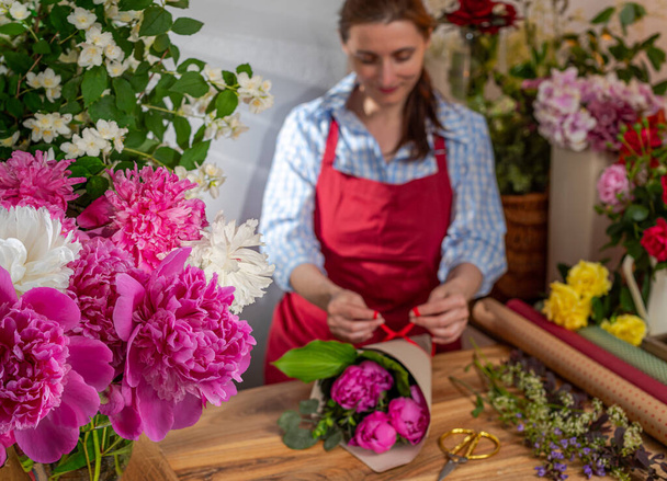Çiçek açan şakayıklı cam vazo, çiçek satıcısı. Çiçek işi. Buketlerin aranjmanı. - Fotoğraf, Görsel
