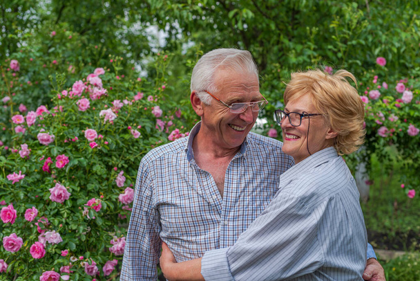 Lächelnde glückliche Seniorin und ein Mann, der sich umarmt, lachen. Frühling oder Sommer sonniger Tag. - Foto, Bild