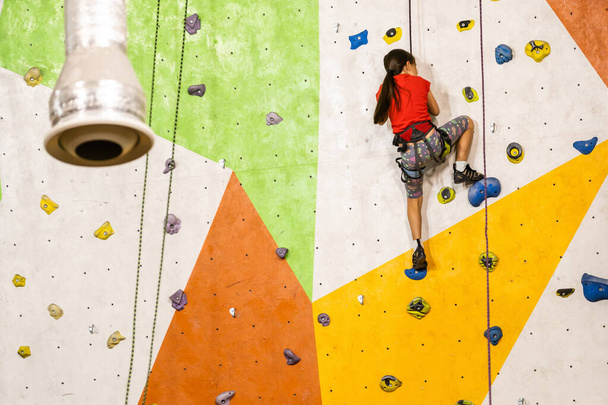 Urheilullinen pieni tyttö kiipeily keinotekoinen lohkare käytännön seinään kuntosalilla - Valokuva, kuva