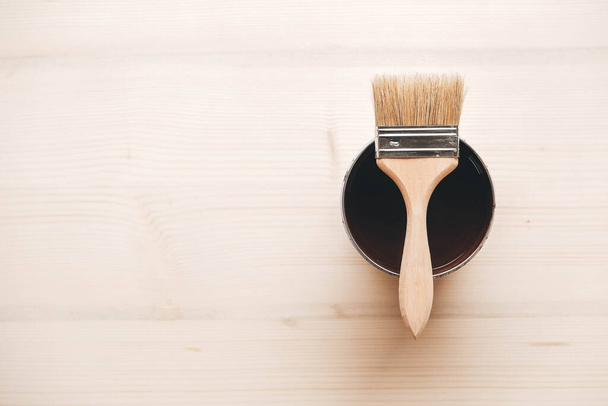 Paint brush on a jar with brown paint on a wooden background. Repairing concept. Top view. Copy, empty space for text. - 写真・画像