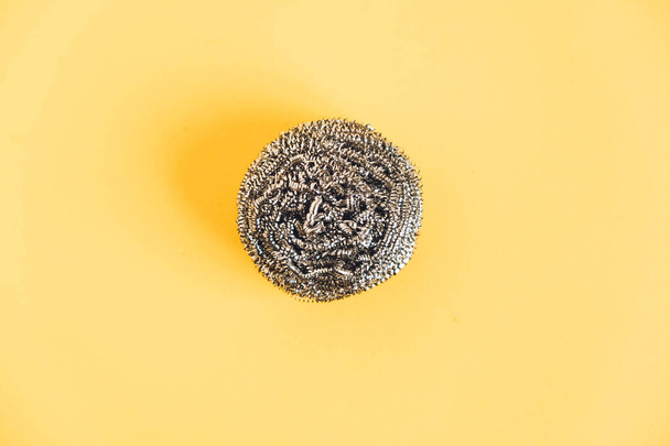 Metal sponge for washing dishes on yellow background. Top view. Copy, empty space for text. - Photo, Image