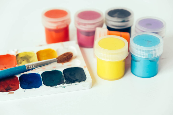 Colorful gouache paints and brush for painting on white wooden table. Copy, empty space for text. - Foto, Imagem