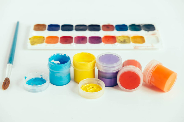 Colorful gouache paints and brush for painting on white wooden table. Copy, empty space for text. - Photo, Image