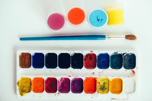 Colorful gouache paints and brush for painting on white wooden table. Copy, empty space for text. - Zdjęcie, obraz