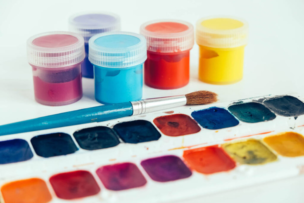 Colorful gouache paints and brush for painting on white wooden table. Copy, empty space for text. - Photo, Image