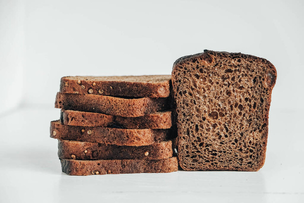 Slices of fresh brown bread with raisins on a white wooden background. Copy, empty space for text. - Foto, Imagem