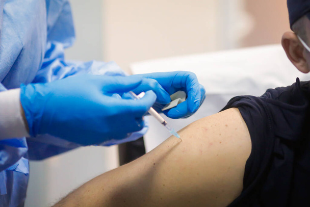 Sars-Cov-2 aşısını bir hastane çalışanından alan bir adamın kas içi enjeksiyonunun detayları.. - Fotoğraf, Görsel