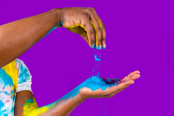 Afro american man celebrate holi festival in violet studio background - Fotó, kép