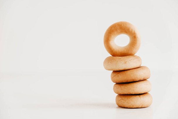 Secado o mini rosquillas redondas en forma de torre sobre un fondo de madera blanca. Copiar, espacio vacío para texto. - Foto, imagen