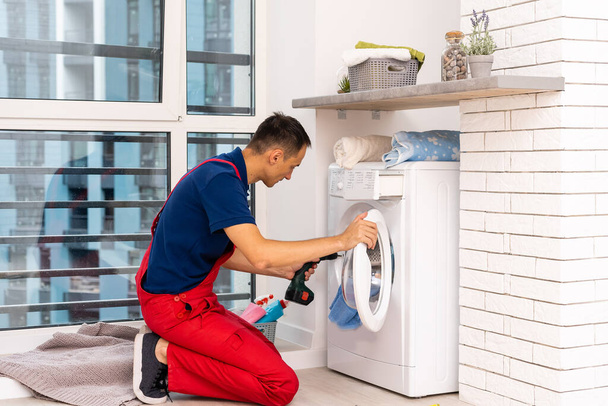masculino adulto reparador com ferramenta e prancheta verificando máquina de lavar roupa no banheiro - Foto, Imagem