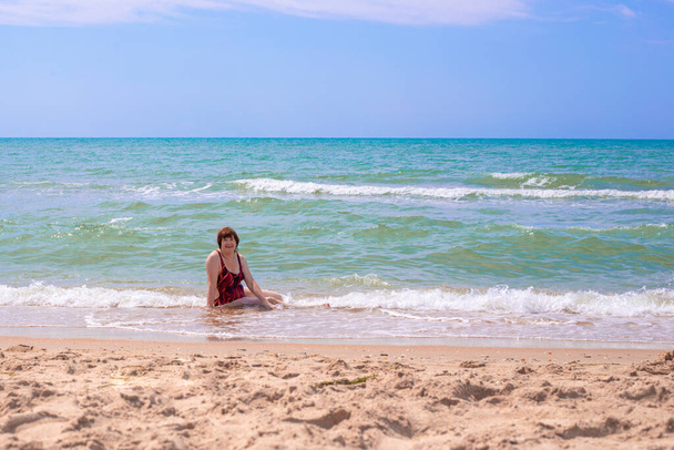 cheerful elderly woman aged 65 plus, bathes in the blue sea, laughs and enjoys a summer day, the end of quarantine and self-isolation - Foto, Bild