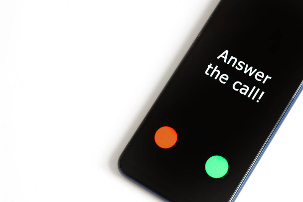 Черный смартфон с входящим звонком и надписью: Ответьте на звонок лежит на белом фоне. Поиск человека или розыгрыш. Крупный план - Фото, изображение