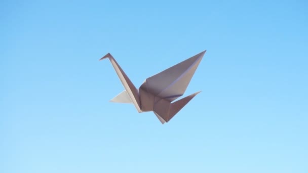 Origami kuşu. Mavi arkaplanda uçan origami kuşu - Video, Çekim