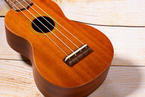 Ukulele, zvýrazněný havajský hudební nástroj s pozadím z lehkého dřeva. - Fotografie, Obrázek