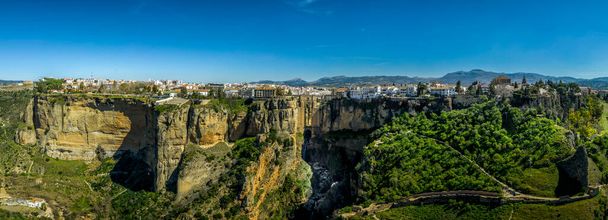 Ronda Spain aerial view of medieval hilltop town surrounded by walls and towers with famous bridge over gorge - Photo, Image