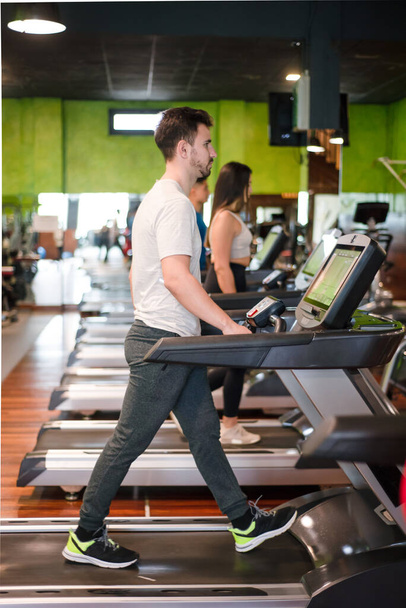 Мужчина осуществляет кардио, бег тренировки на беговой дорожке в фитнес-зале.  - Фото, изображение
