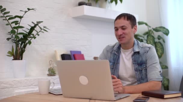Technologie, Fernjob und Lifestylekonzept - glücklicher Mann mit Laptop im Videochat und winkender Hand im Home Office - Filmmaterial, Video