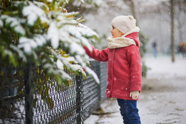 Adorable toddler girl on a day with heavy snowfall. Happy child playing with snow. Winter activities for kids. - 写真・画像