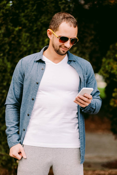 Homme portant un t-shirt blanc tenant téléphone maquette - Photo, image