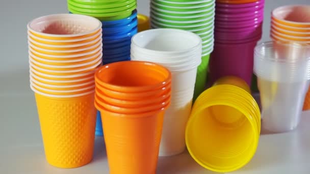 Disposable cups. Stack of colorful plastic cups on the table. Rotation. Closeup - Footage, Video
