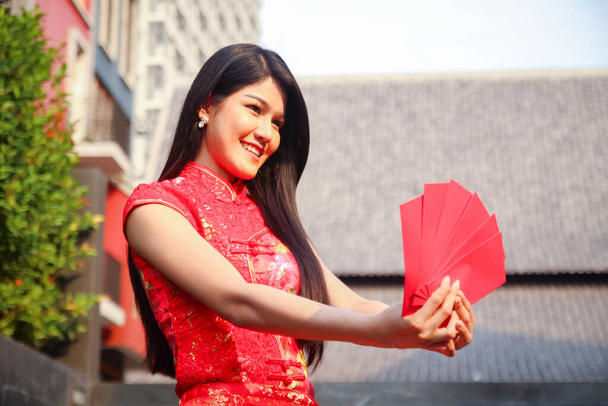 Elinde kırmızı bir zarf tutan Çinli bir elbise giyen güzel bir kadın. Çin yeni yılı. Boşluğu kopyala - Fotoğraf, Görsel