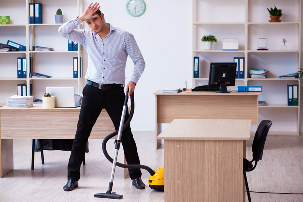 Junge männliche Angestellte putzen Büro während Pandemie - Foto, Bild