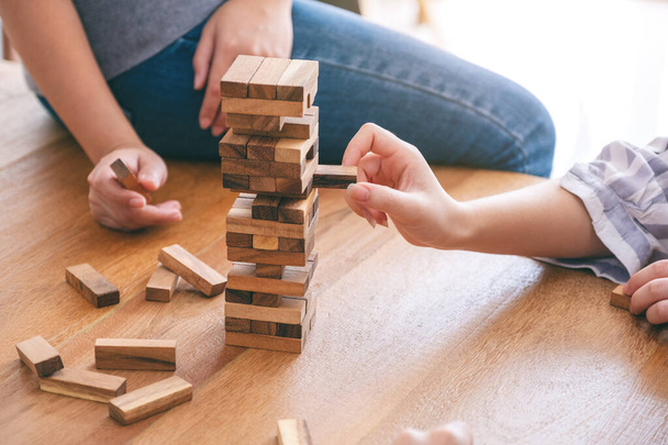 Groep vrienden zitten en spelen Tumble toren houten blok spel samen met het gevoel gelukkig - Foto, afbeelding