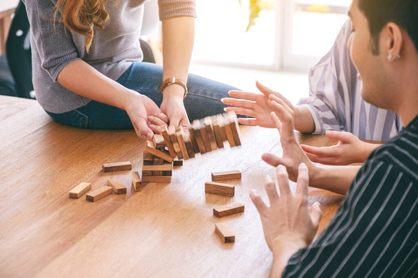 Group of friends sitting and playing Tumble tower wooden block game together with feeling happy - Foto, Bild