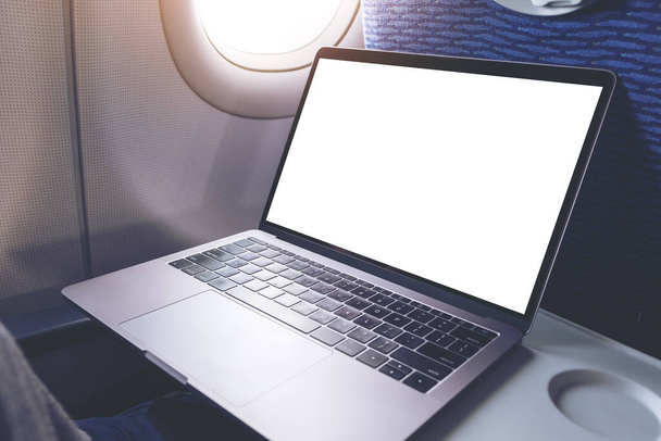 Mockup image of laptop computer with blank white desktop screen in the cabin - 写真・画像