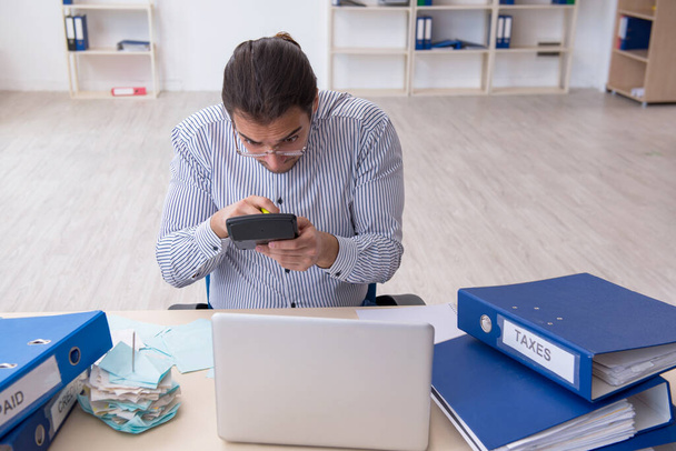 Молодий чоловік букмекер обчислює податкові платежі в офісі
 - Фото, зображення
