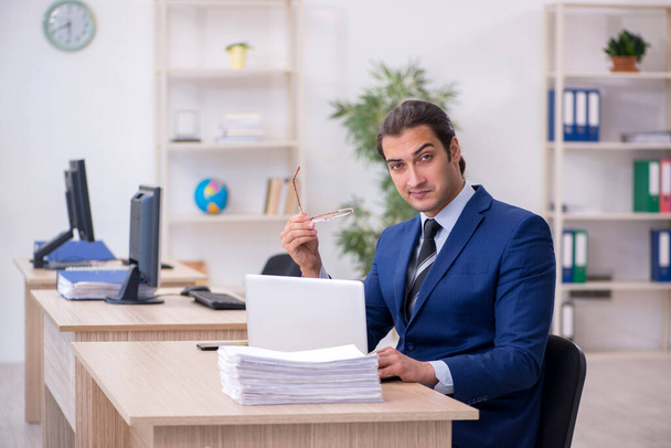 Jonge mannelijke werknemer werkzaam in het kantoor - Foto, afbeelding